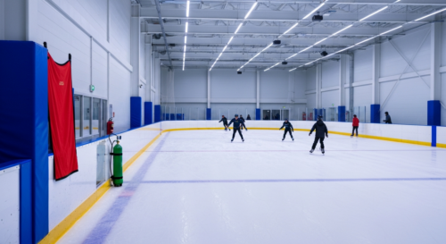 A detailed, photorealistic image of a modern, well-maintained indoor sports facility with a smooth skating rink surface, bright lighting, safety padding on walls, and emergency equipment visible in th