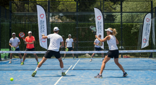 Photorealistic image of a padel court during a charity tournament in Marbella, with players in action, a sunny day, and banners with heart symbols and the text 'Corazón Fuerte'.