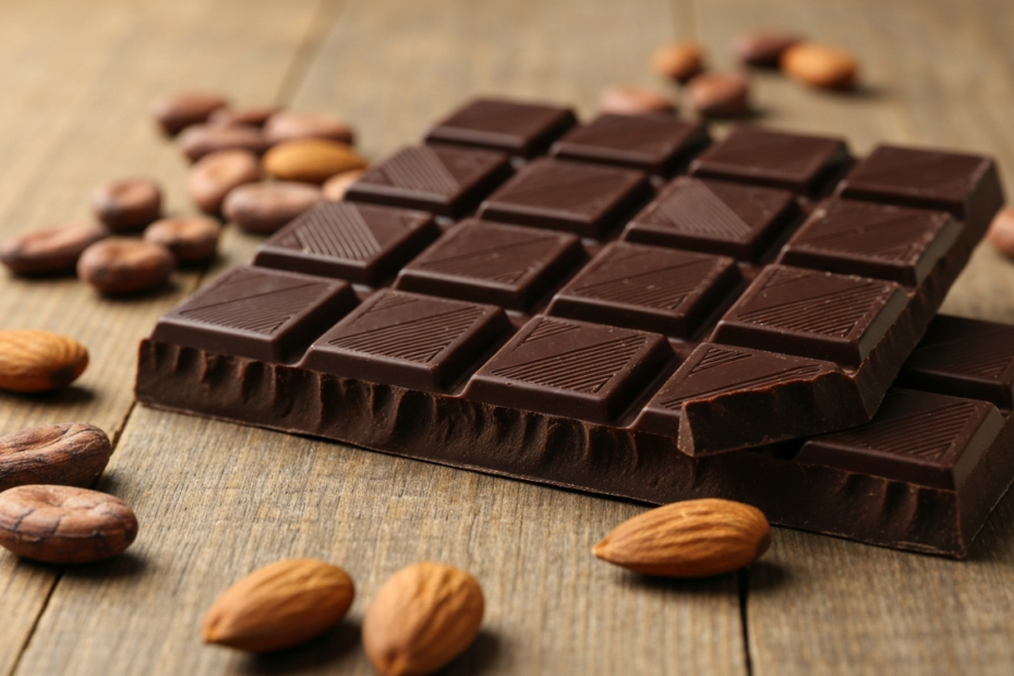 A close-up, photorealistic image of high-quality artisanal dark chocolate bars with 70% cocoa content, arranged on a rustic wooden table, with cocoa beans and a few whole almonds scattered around, nat