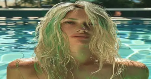 A closeup of a woman's blonde hair showing green tones after swimming, with a swimming pool and water reflections in the background, hyper-realistic, natural sunlight, no text