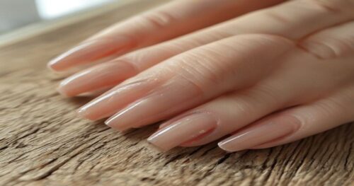 Extreme close-up macro photograph of natural unpainted fingernails with distinct horizontal ridges (Beau's lines) across all nails. Hands resting on a neutral wooden table, soft diffused window light,